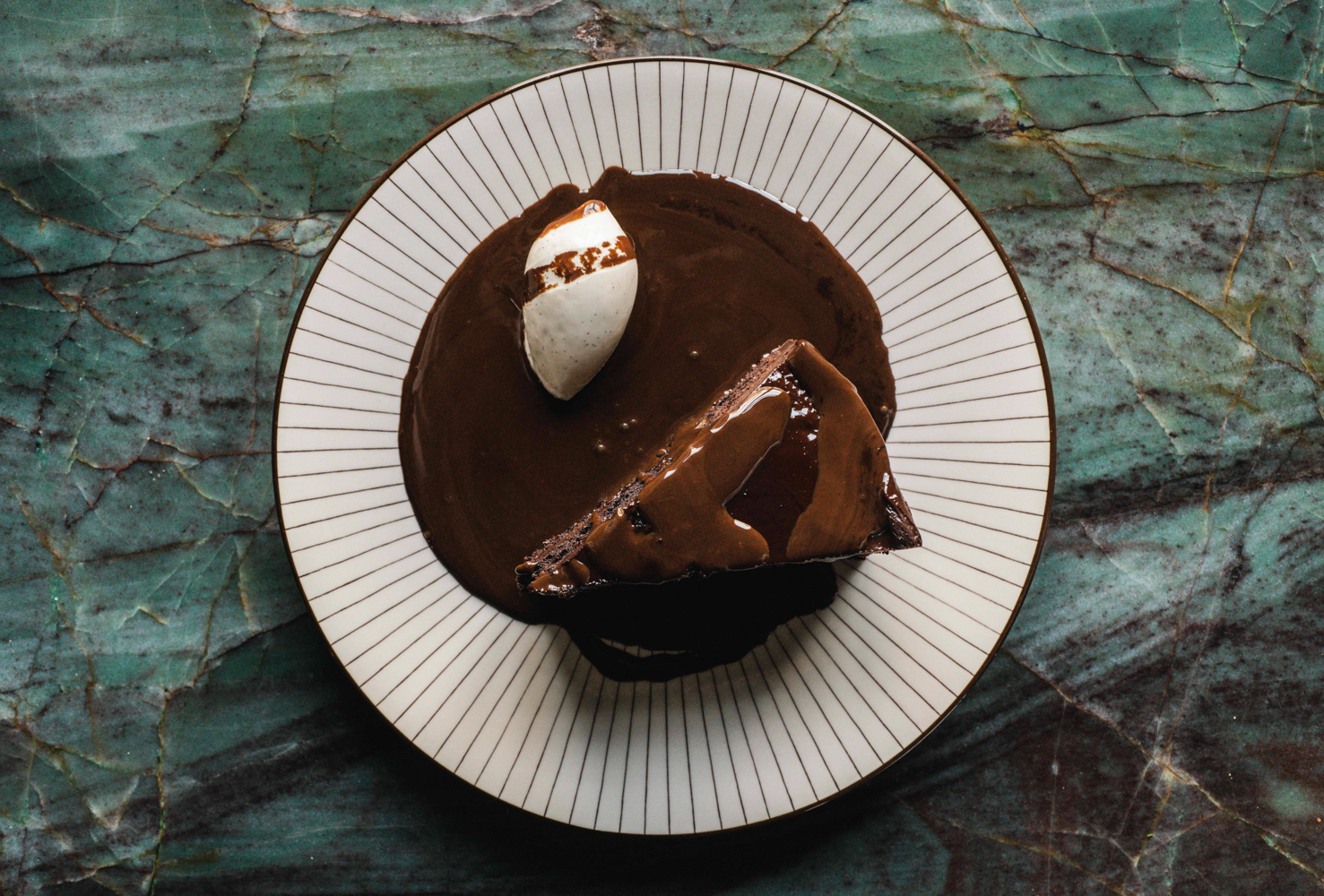 Tarta de chocolate acompañada con una bola de helado.