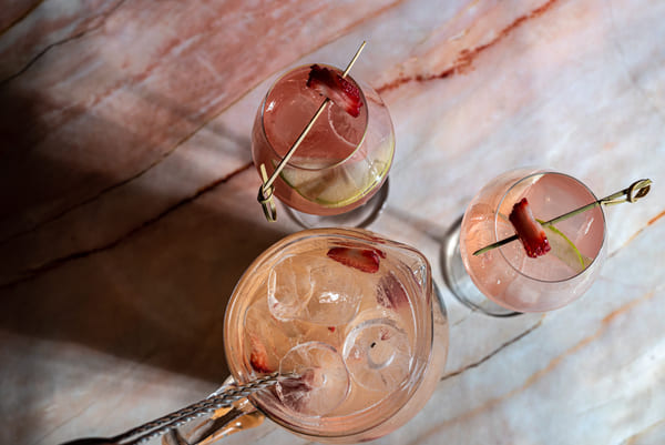 Bodegón de cristalería compuesto por una jarra y dos copas servidas con bebida fría de fresas.